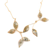 a necklace with marble filled leaves with a gold chain on a white background
