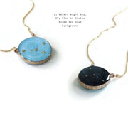 Two gold necklaces set on a white background. Necklace on the left is a sky blue color and the right is night sky they both have gold beads placed in the Cancer constellation. Custom stamping on the side says "Seven ninteen". Text on the white background says "1) Select Night Sky, Sky Blue or Double Sided for your background