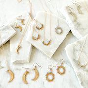 Aztec jewelry collection gold and silver moon and sun earrings and necklaces placed on broken pieces of marble