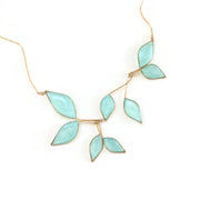 Gold necklace with 8 hanging leaf shaped pendants filled with clear sky blue resin with subtly  sparkling mica on a white background